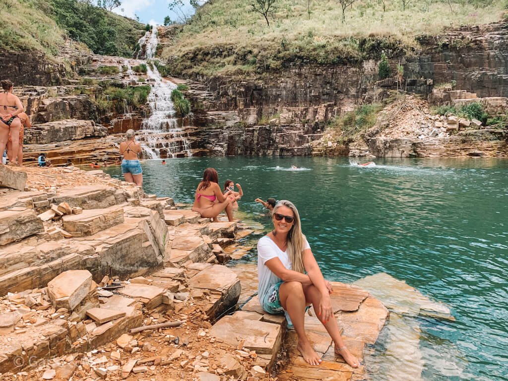 mulher sentada nas pedras de uma cachoeira